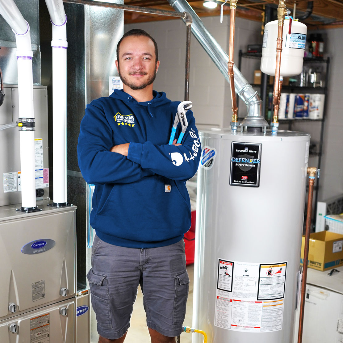 Plumber with a wrench standing next to a Water Heater