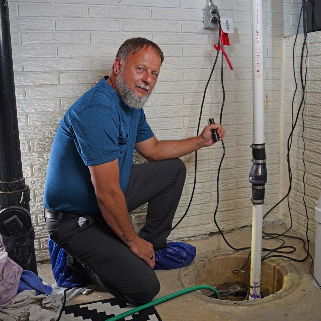 Plumber Holding a Flash Light next to a sump pump