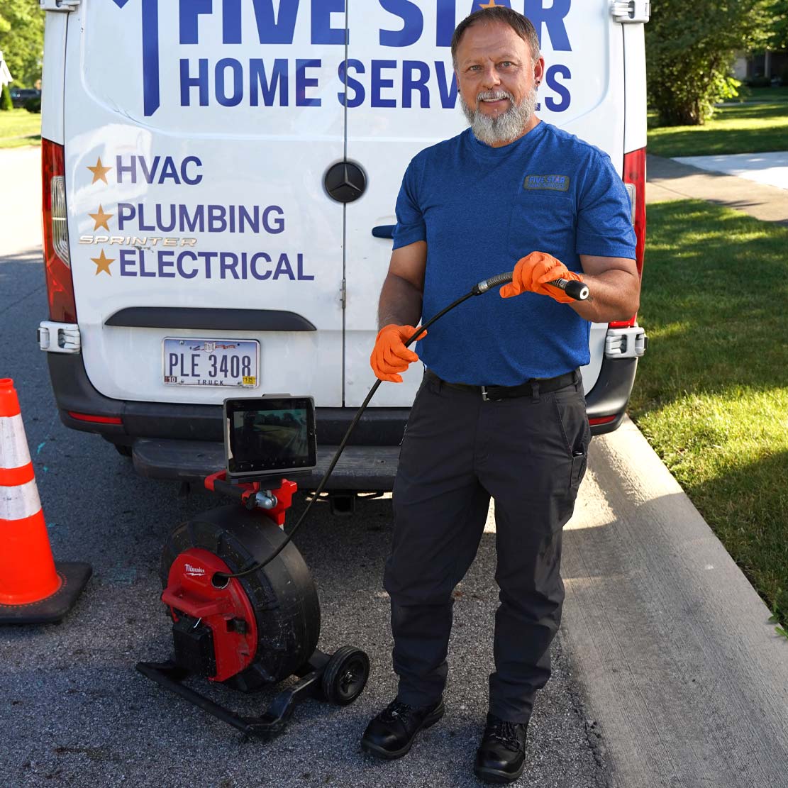 Plumbing Holding Sewer Line Inspection Tool In Front of a van