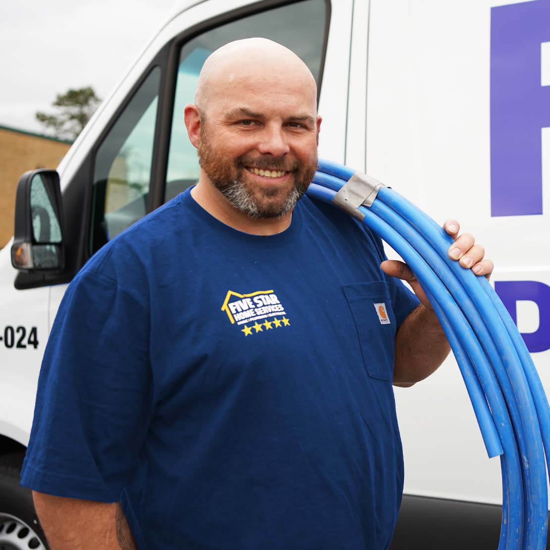 Plumber holding plumbing piping by a van