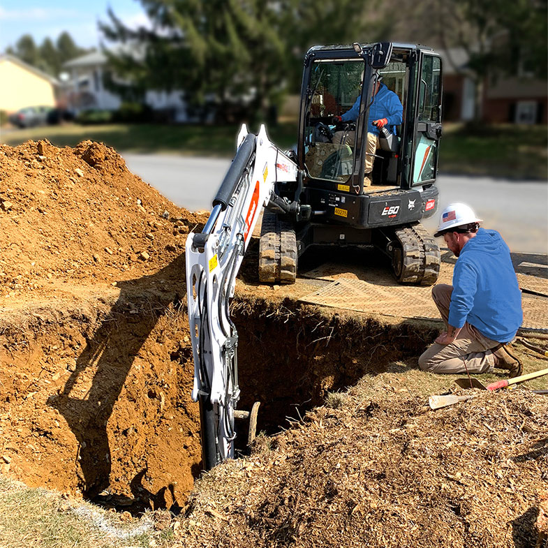 Two Plumbers with an Excavator Clearing a Main Line